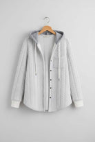 Light grey Highland Plaid Shacket with hood, button-front closure, and front pocket hanging on wooden hanger against grey wall