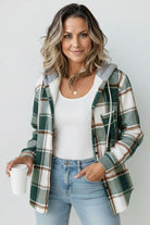Woman wearing cozy Highland Plaid Shacket with hood, button-front, and plaid pattern, styled casually with jeans and white top