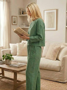 woman wearing loose solid color green two-piece set reading book in cozy living room