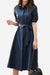 Woman wearing a navy radiance belted shirt dress with short sleeves and a detachable waist belt, holding a black handbag.