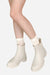 White non-slip rain boots with SuperGrip soles worn with white socks on model legs against a white background