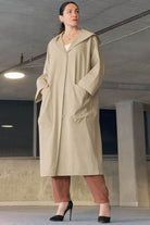 Woman wearing oversized beige water resistant windbreaker jacket with hood and large front pockets