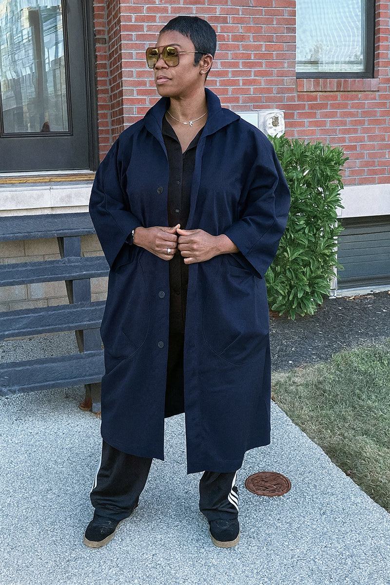 Oversized heritage windbreaker jacket in navy blue with snap-button closure and longline design worn by model outdoors