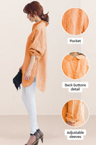 Side view of oversized linen shirt in soft orange with back button details, adjustable sleeves, and pocket, styled with white pants and heels