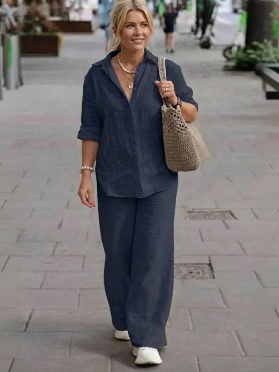 Woman wearing oversized 100% cotton navy blue shirt and wide-leg pants co-ord set walking on city street with beige tote bag and white sneakers