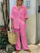 Woman wearing oversized 100% cotton pink shirt and wide-leg pants co-ord set with woven handbag and sandals outdoors