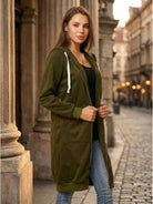 Woman wearing oversized long zip sweatshirt hoodie with front pockets and drawstring hood in urban setting