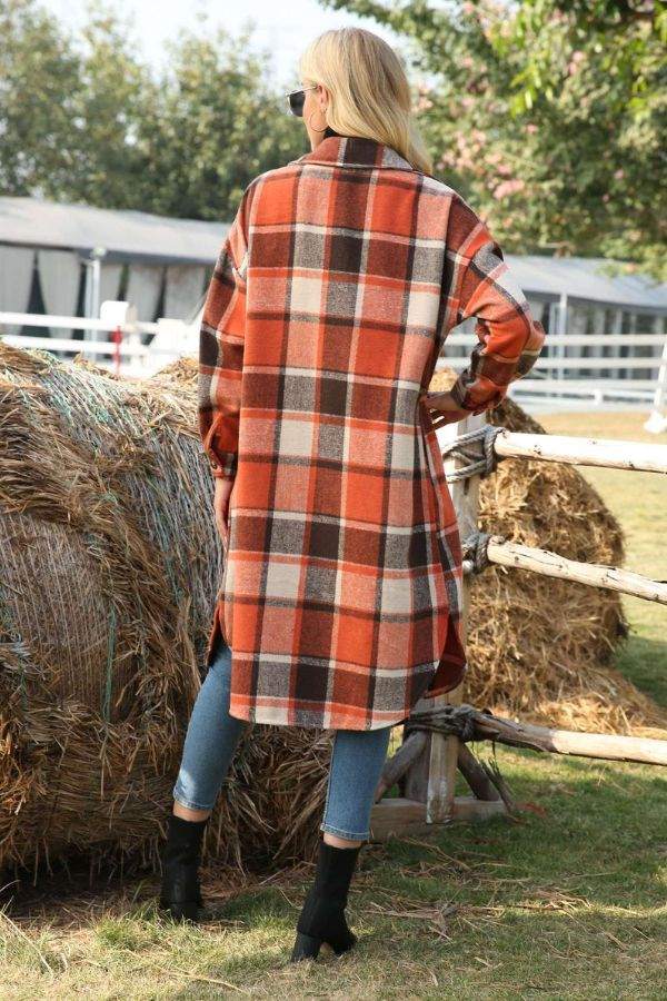 Woman wearing oversized medium-length plaid overshirt outdoors near hay bales