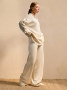 woman wearing plush and preppy camel two-piece set with polo collar and wide-leg pants standing against beige background