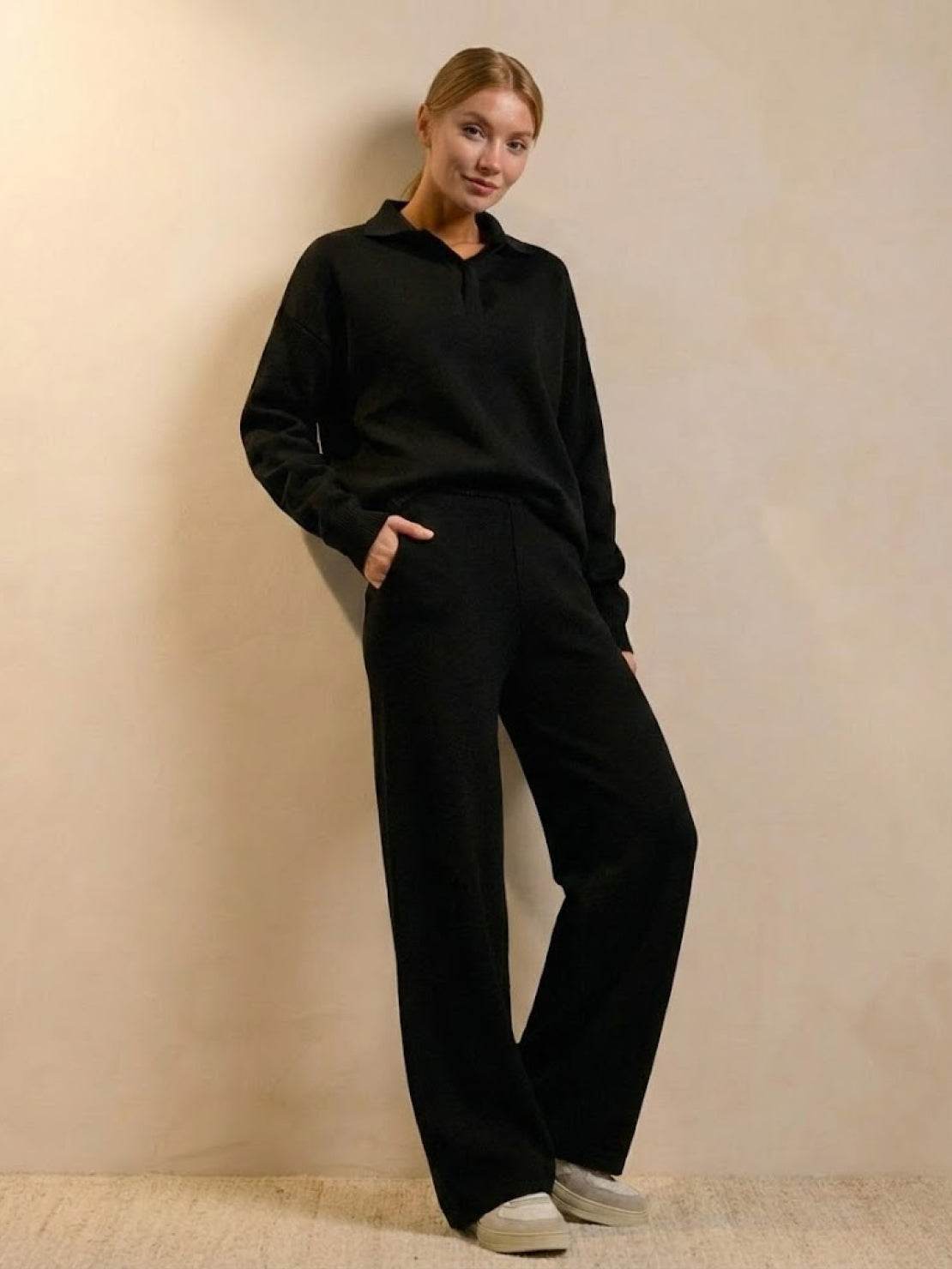 Female model wearing plush and preppy camel two-piece black loungewear set with polo collar and wide-leg pants.