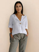 Woman wearing pure linen age-defying button detail shirt in white with rolled sleeves and olive pants