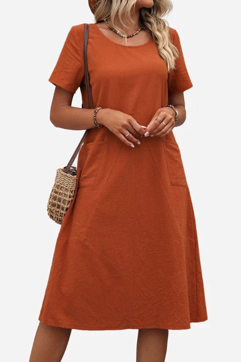 Radiant Escape Panelled Beach Dress in rust orange, midi length with round neckline and A-line skirt, styled with a woven shoulder bag.