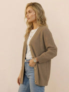 Relaxed fit oversized knitwear cardigan in beige with button-down front, worn over a white top and jeans.