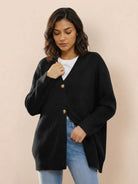 Relaxed fit oversized black knit cardigan with button down front, styled on woman wearing jeans and white top.