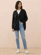 Relaxed fit oversized black knit cardigan with buttons worn over white top and blue jeans
