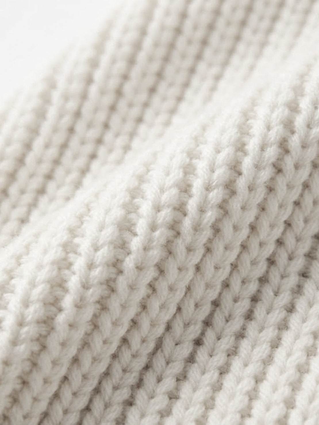 Close-up of soft, white relaxed fit oversized knitwear cardigan fabric texture