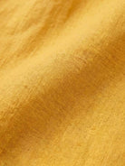 close-up of relaxed loose breathable linen fabric in warm yellow color