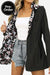 Reversible floral raincoat with solid black exterior and floral print interior, featuring a hood and drawstring waist for a feminine silhouette.