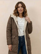 Woman wearing a brown Sherpa-lined hooded teddy coat with plush lining and front pockets