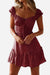Woman wearing a red sweetheart collar printed ruffled mini dress with short sleeves and a high waist design.