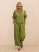 Woman wearing olive green loose fit co-ord set with short sleeves and wide-leg trousers.