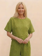 Woman wearing green loose fit co-ord set with short sleeves and wide-leg pants against a neutral background