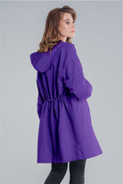 Woman wearing a purple oversized Rain Couture Windbreaker with hood and adjustable waist back view