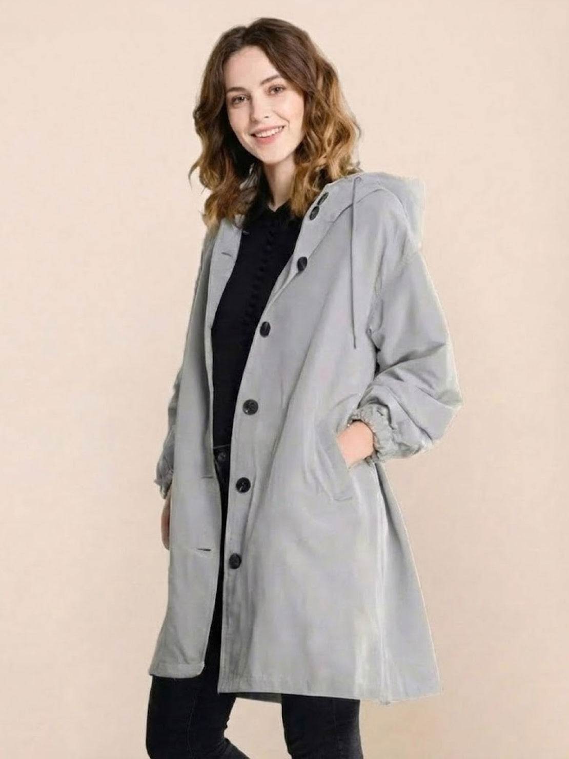 Woman wearing grey oversized Rain Couture Windbreaker with hood and buttons over black outfit