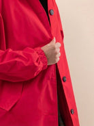 Close-up of a vibrant red Rain Couture Windbreaker with button closure and elastic cuff.