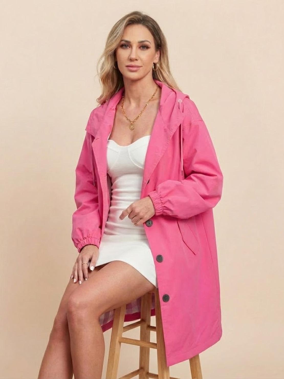 woman wearing pink oversized Rain Couture Windbreaker jacket sitting on wooden stool