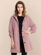 Woman wearing pink oversized Rain Couture Windbreaker with hood and button closure