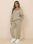 Woman wearing ultra-soft and comfy co-ord tracksuit set in khaki with white sneakers against a beige background