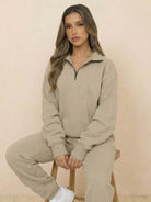 Woman wearing beige ultra-soft and comfy co-ord tracksuit set with zip-up top sitting on stool.