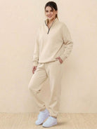Ultra-soft beige co-ord tracksuit set with zip neck and relaxed fit, styled with white sneakers, perfect for cozy casual wear.
