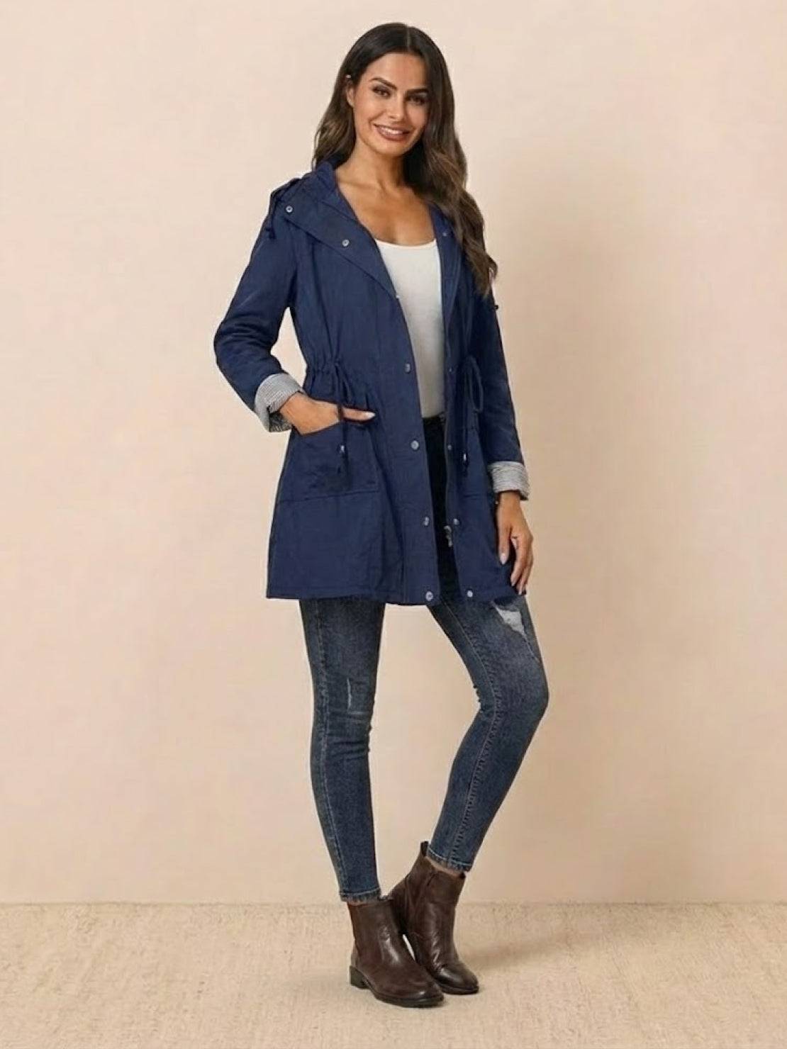 woman wearing navy water resistant windbreaker jacket with hood and pockets paired with jeans and ankle boots