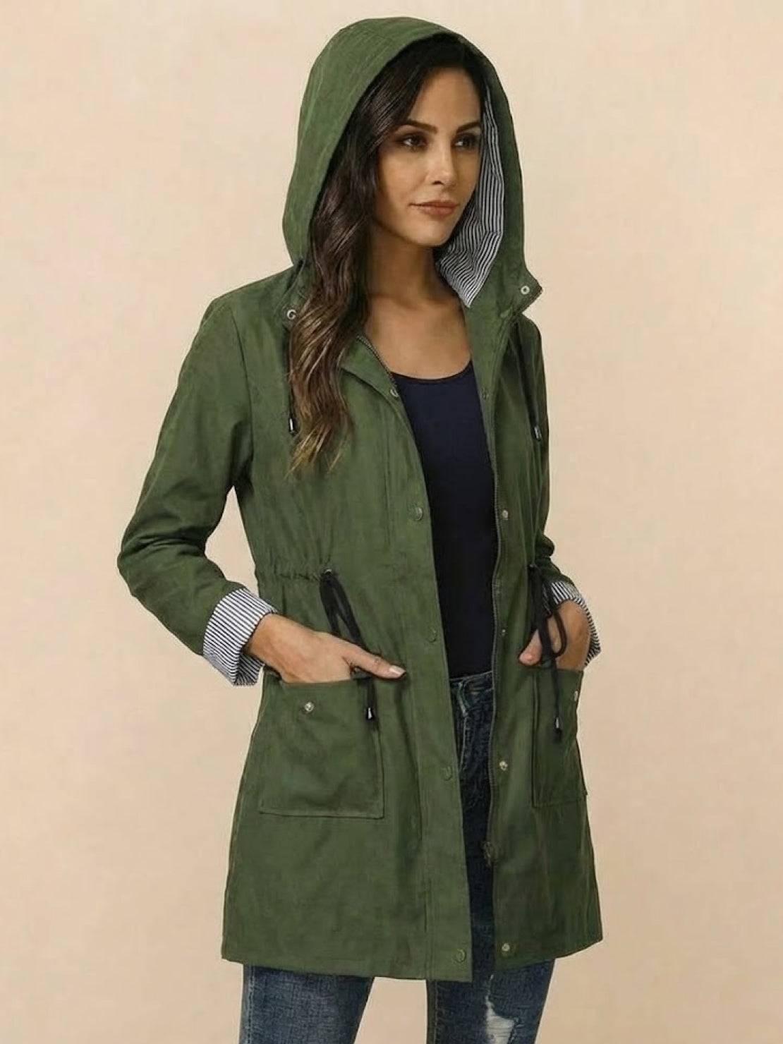 Woman wearing a green water resistant windbreaker with hood and striped lining